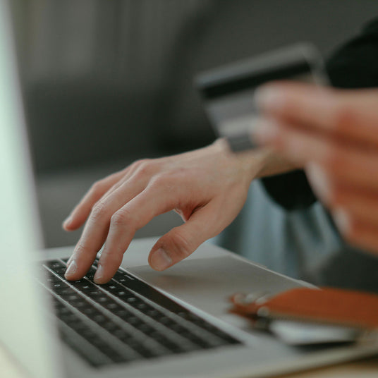Hands using a laptop while holding a payment card, representing responsible and transparent procurement.