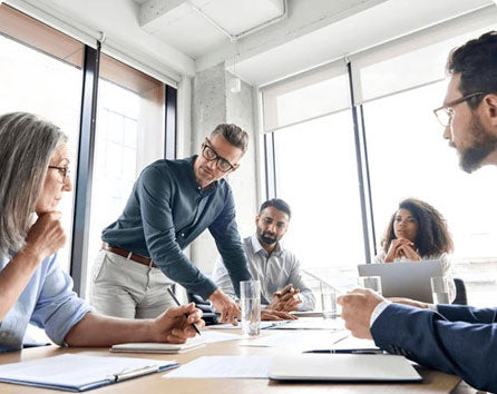 People in a workplace meeting discussing documents around a table